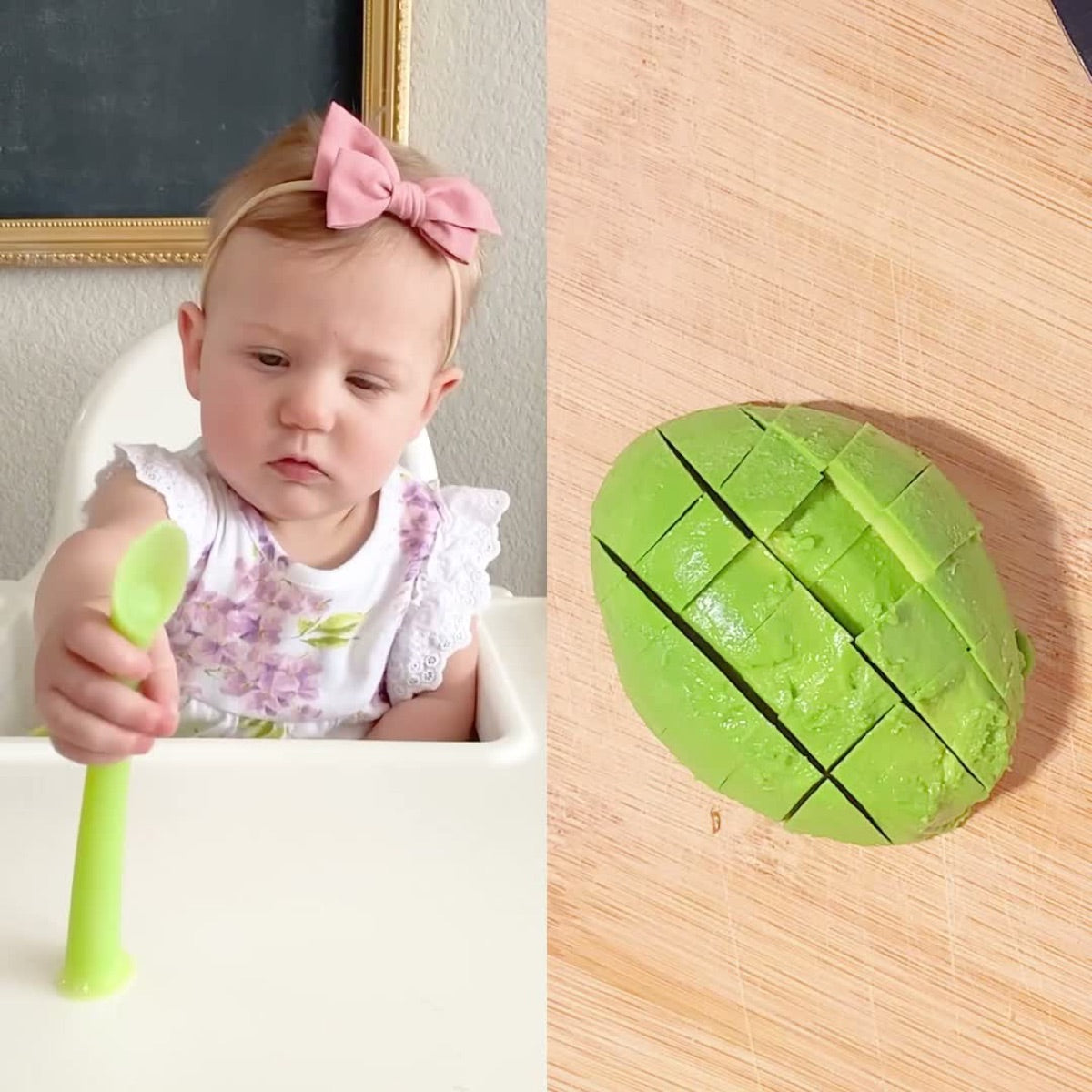 Baby holding an Olababy training spoon next to sliced avocado cut for baby-led weaning