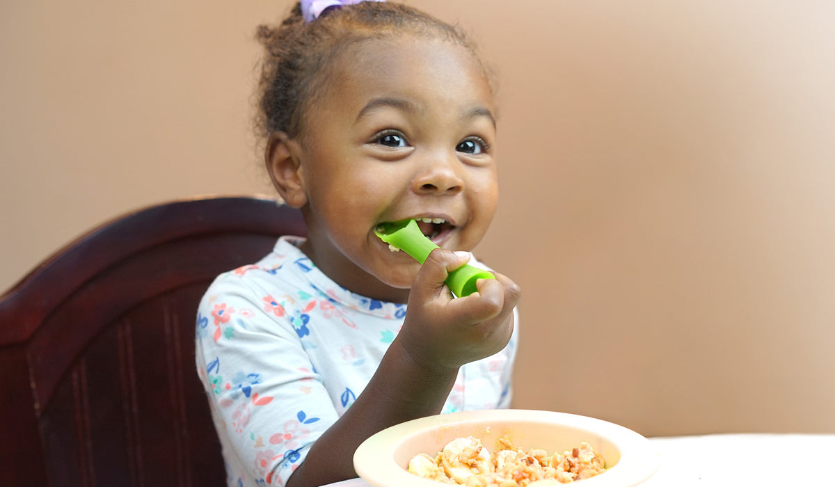 Infant practicing independent self feeding and soothing sore teething gums with an Olababy silicone spoon